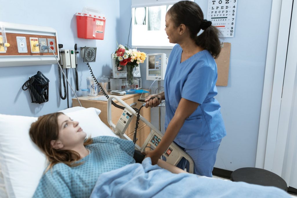 woman in blue scrub suit holding white and gray hospital bed