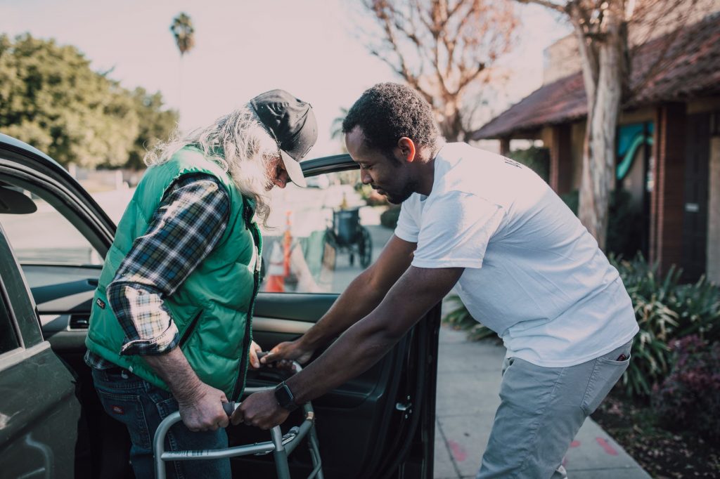 man assisting person with walker